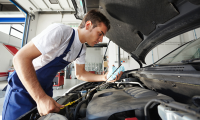 A professional mechanic working on a car while wearing branded work clothes from Formscorp.